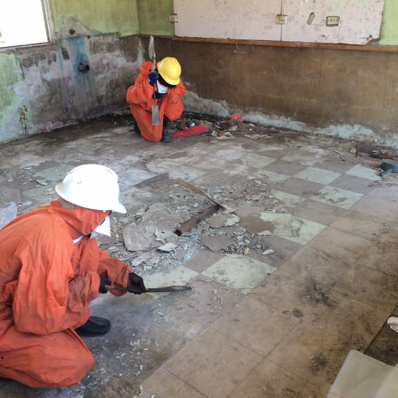 Damaged asbestos flooring materials are safely removed at a building adjacent to the site of the fire. Photo: Brad Wallace.