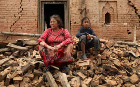 Nepalese woman and child on rubble in the village of Sathighar, north of Katmandu, 29 April.