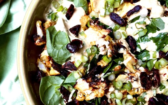 A delicious salad of spice-roasted cauliflower with baby spinach leaves, chopped dates, spring onions and a curry yoghurt mayo dressing, in a green Tony Sly bowl.