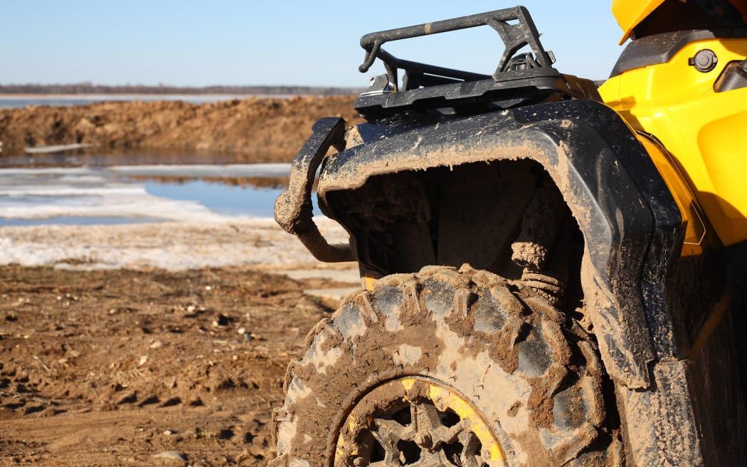 Sport, tourism and activity - Closeup motorised quadricycle in dirt on frozen the rivers a background