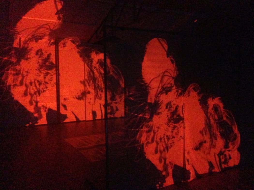 A production still from In Transit, showing projected images on clear screens.