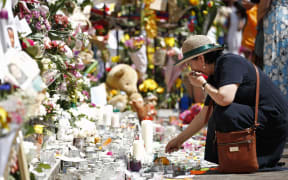 A woman lays flowers in tribute to the victims of the June 14 Grenfell Tower block fire in Kensington, west London, on June 17, 2017.