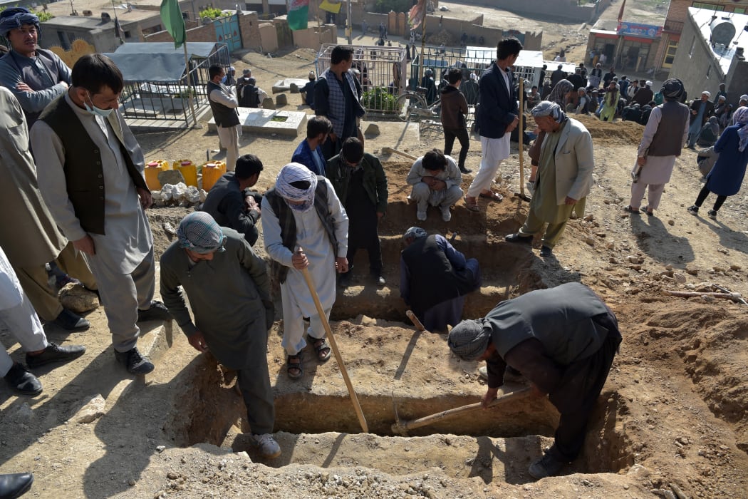 Shiite mourners and relatives dig graves for girls who died in an attack outside a girls' school in Dasht-e-Barchi on the outskirts of Kabul on 9 May, 2021.