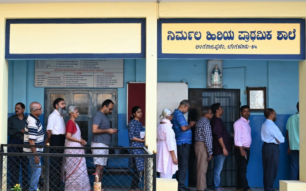 Voters queue to cast their ballot outside a polling station during the second phase of voting of India's general election in Bengaluru on April 26, 2024. (Photo by Idrees MOHAMMED / AFP)