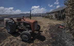 A tractor stands nearly intact after fire raged around this property in the Port Hills