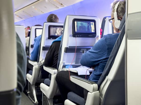Airplane passengers in seats watching movies, wearing headphones.