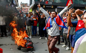 People displaying Nepal's national flag burn tyres during a demonstration to condemn the police's deadly crackdown on protesters in Kathmandu on September 9, 2025, a day after demonstrations over social media prohibitions and corruption by the government. Nepal rolled back its social media ban on September 9, a day after at least 19 people were killed in youth protests demanding that the government lift its restrictions and tackle corruption. All major social media apps were working, an AFP reporter in Kathmandu said, as the government ordered a probe into the violence that saw police launch one of the deadliest crackdowns on protesters for years. (Photo by Prabin RANABHAT / AFP)