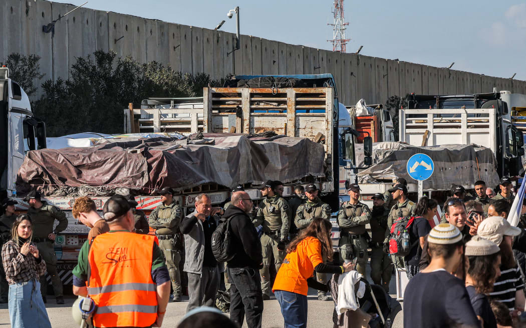 Israeli security forces stand by Egyptian trucks bringing in humanitarian aid supplies to the Gaza Strip, on the Israeli side of the Kerem Shalom border crossing with the Palestinian territory on 6 February, 2024, as right-wing Israeli protesters gather to block the trucks from entering.