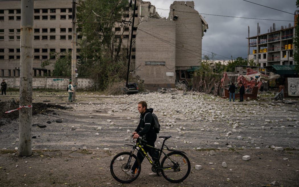 A resident pushes his bicycle next to a crater following a missile strike in Dnipro on 10 October, 2022, amid Russia's invasion of Ukraine.