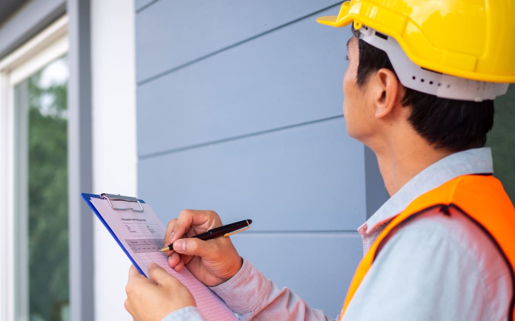 The inspector or engineer is checking the building structure and the requirements of the wall paint.