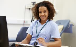 Portrait Of Female Nurse Working At Desk In Office