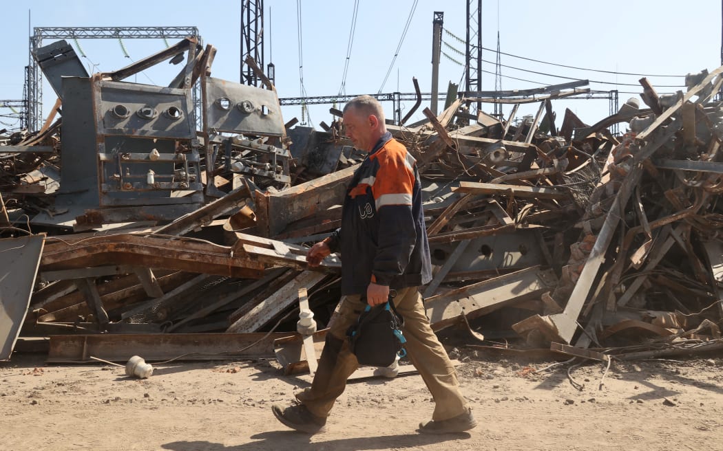 A utility worker is walking past a pile of debris at an energy facility that is being repaired after being damaged by Russian shelling in Kharkiv, northeastern Ukraine, on April 10, 2024. NO USE RUSSIA. NO USE BELARUS. (Photo by Ukrinform/NurPhoto) (Photo by Vyacheslav Madiyevskyy / NurPhoto / NurPhoto via AFP)