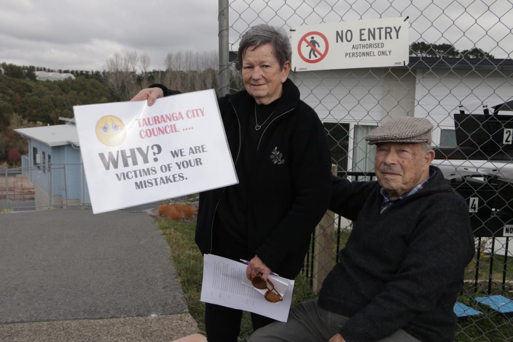 Former Bella Vista residents hold signs expressing their frustration after a compensation for the failed development was rejected.