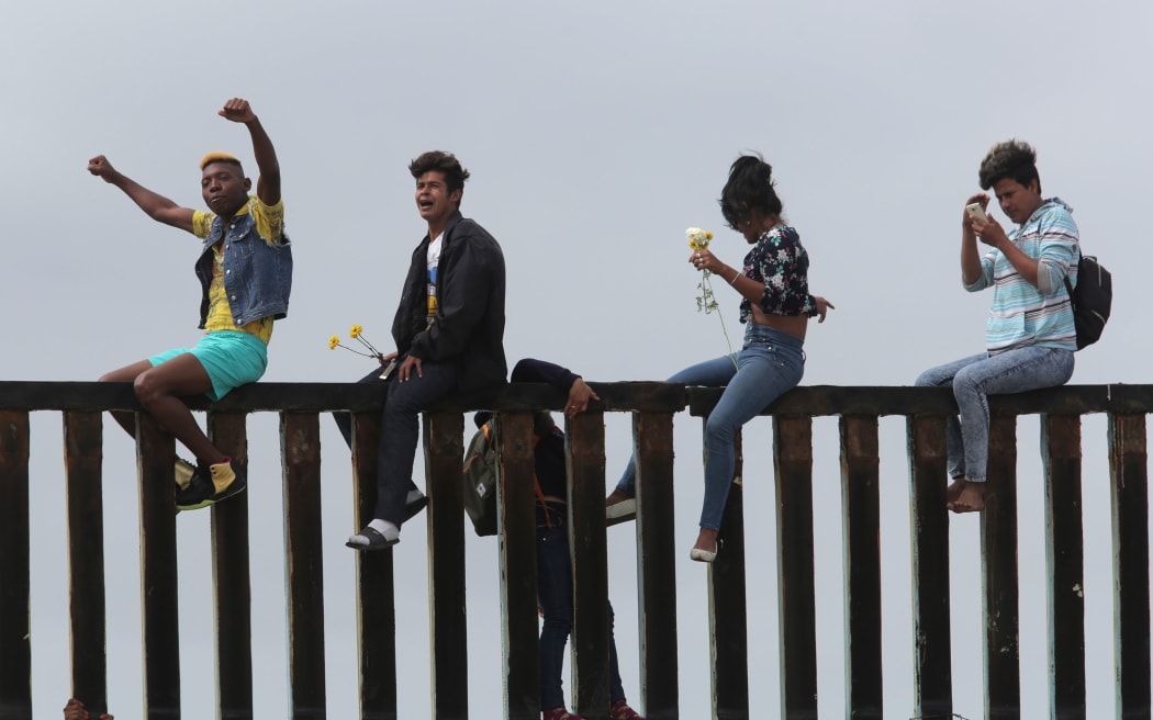 Pro-migrant caravan demonstrators rally on the Mexican side of the border wall on April 29, 2018 in San Diego, California.