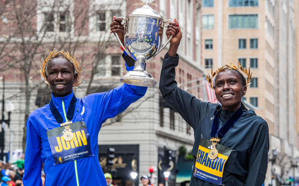 Kenyan's John Korir and Sharon Lokedi pose with the trophy after winning their respective races at the 2026 Boston Marathon.