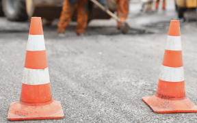 Road cones with road workers in background.