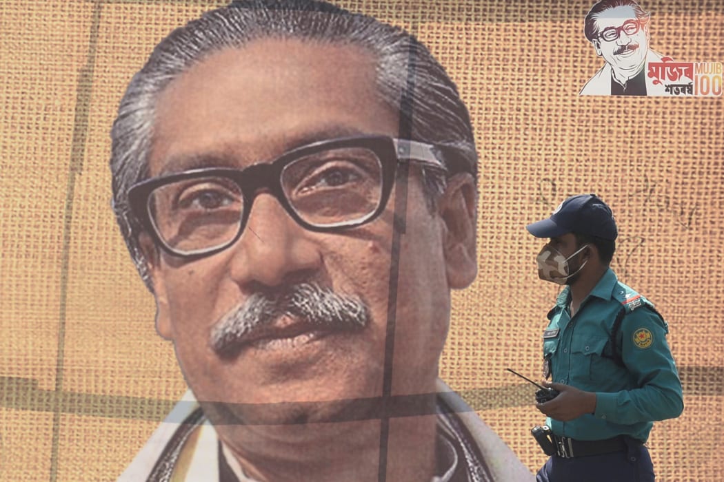 At a banner with a picture of Bangladesh's founder Sheikh Mujibur Rahman in Dhaka.