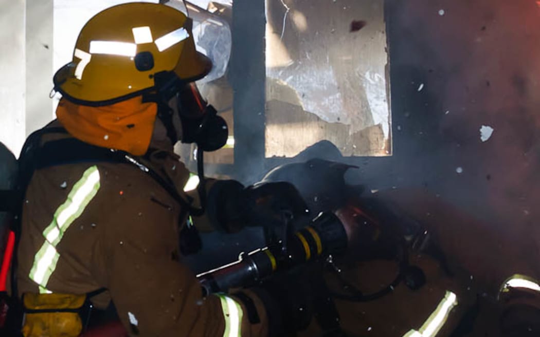 Firefighters carrying out 'hot fire training', using breathing apparatus in a burning room.