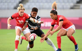 Two British players fight for the ball with Fiji's Reapi Uluinasau in the women's bronze medal rugby sevens match at the Tokyo Olympics 2021.