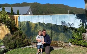 Artist Hana Carpenter and her son in front of the mural of the hills.