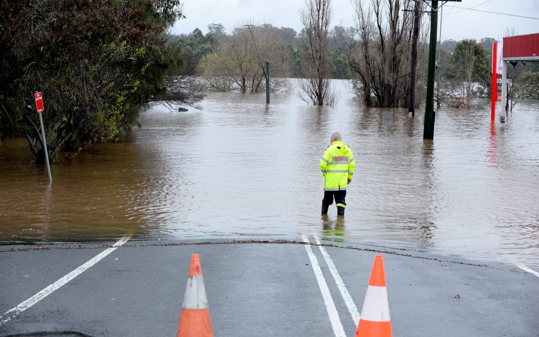 A rescue worker examines a flooded area due to torrential rain in the Camden suburb of Sydney on July 3, 2022. - Thousands of Australians were ordered to evacuate their homes in Sydney on July 3 as torrential rain battered the country's largest city and floodwaters inundated its outskirts. (Photo by Muhammad FAROOQ / AFP)