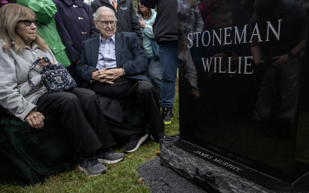 People look at a headstone for 'Stoneman Willie' (James Murphy), during his funeral service in Reading, Pennsylvania, on October 7, 2023. "Stoneman Willie" died in a Pennsylvania jail more than 100 years ago after being arrested for pickpocketing. Upon his arrest, he provided a fake name, and later died of kidney failure at the Berks County Prison. The body has been on display to visitors since 1895, but after an investigation of his mummified remains, he has been identified. (Photo by ANDREW CABALLERO-REYNOLDS / AFP)