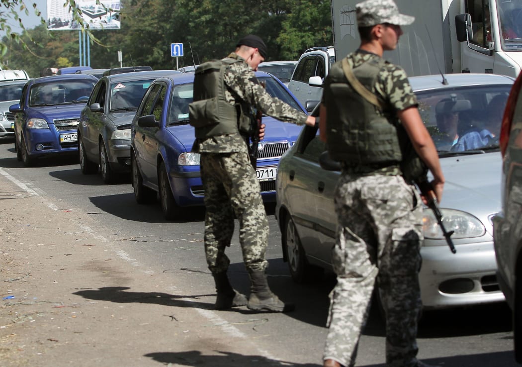 Ukrainian troops stop cars at a checkpoint as people flee the southern Ukrainian city of Mariupol in the Donetsk region.
