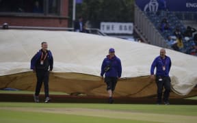 Groundstaff move the covers as rain stopped play during the 2019 Cricket World Cup first semi-final between India and New Zealand at Old Trafford in Manchester on July 9, 2019.