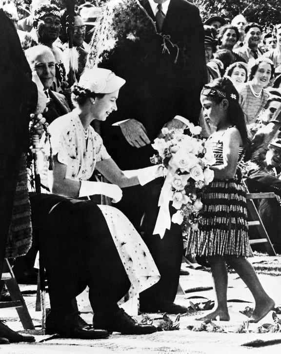A little girl offers flowers at a welcoming ceremony in honour of Queen Elizabeth II (left), on 6 January, 1954 in Waitangi, during her visit in New Zealand.