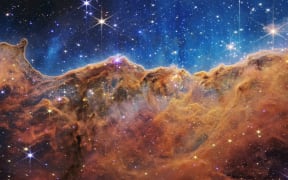 This image released by NASA on July 12, 2022, from the James Webb Space Telescope (JWST) shows a landscape of “mountains” and “valleys” speckled with glittering stars which is actually the edge of a nearby, young, star-forming region called NGC 3324 in the Carina Nebula. Captured in infrared light by the JWST, this image reveals for the first time previously invisible areas of star birth. - The JWST is the most powerful telescope launched into space and it reached its final orbit around the sun, approximately 930,000 miles from Earths orbit, in January, 2022. The technological improvements of the JWST and distance from the sun will allow scientists to see much deeper into our universe with greater detail. (Photo by Handout / NASA / AFP) / RESTRICTED TO EDITORIAL USE - MANDATORY CREDIT "AFP PHOTO / NASA" - NO MARKETING NO ADVERTISING CAMPAIGNS - DISTRIBUTED AS A SERVICE TO CLIENTS