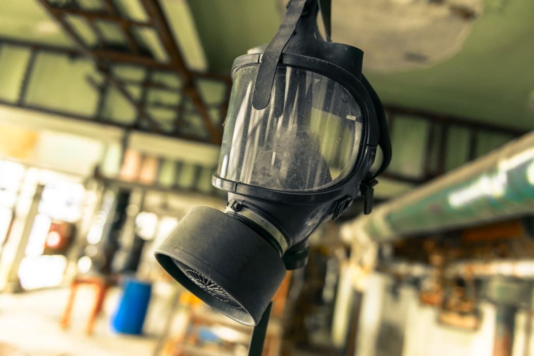 A gasmask - like those used when working with or cleaning up after methamphetamine (meth, or P) - hangs from the ceiling in an old building.