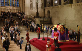 Members of the public pay their respects as they pass the coffin of Queen Elizabeth II as it Lies in State inside Westminster Hall, at the Palace of Westminster in London on September 15, 2022. - Queen Elizabeth II will lie in state in Westminster Hall inside the Palace of Westminster, until 0530 GMT on September 19, a few hours before her funeral, with huge queues expected to file past her coffin to pay their respects. (Photo by Odd ANDERSEN / POOL / AFP)