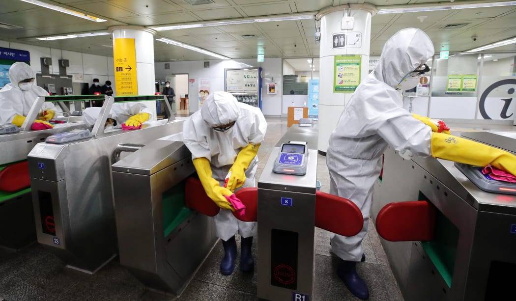 Workers wearing protective gear disinfect ticket gates as part of preventive measures against the spread of the Covid-19 coronavirus, at a subway station in Seoul on February 28, 2020.