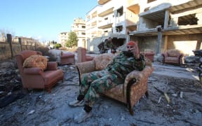 A member of the Syrian pro-government forces sits on a sofa in the strategic town of Salma.