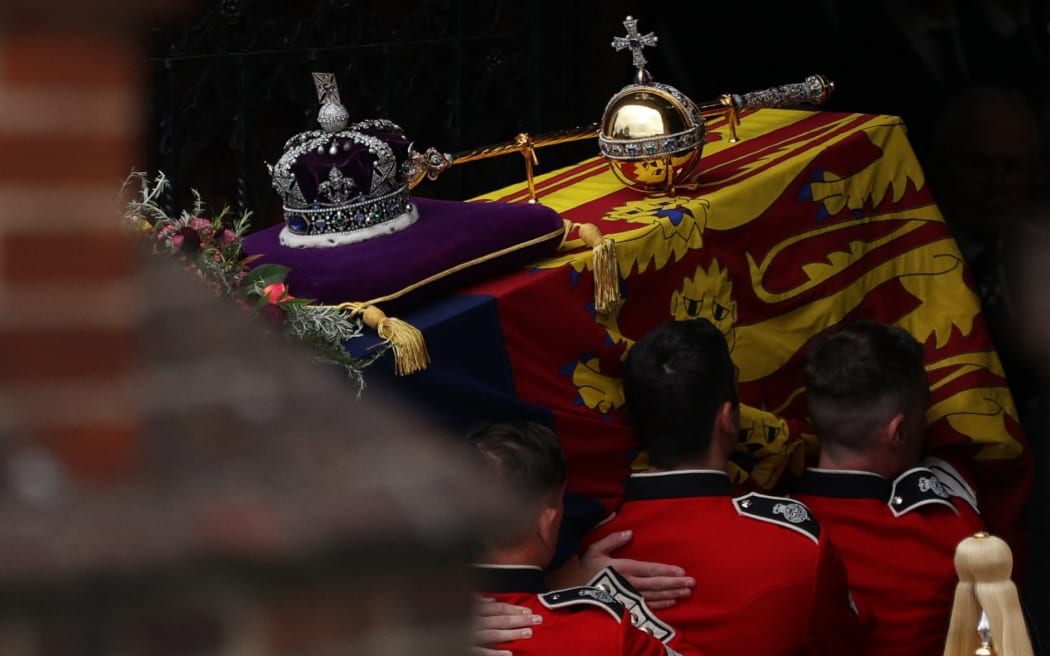 The Bearer Party take the coffin of Queen Elizabeth II, draped in a Royal Standard and adorned with the Imperial State Crown and the Sovereign's orb and sceptre, into St George's Chapel inside Windsor Castle on September 20, 2022.