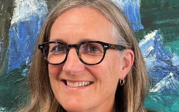 Dr Penelope Jackson is a smiling woman in black-framed glasses with long blonde hair.