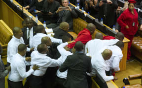 Members of the Economic Freedom Fighters, wearing red uniforms, clash with security forces during South African President's State of the Nation address.