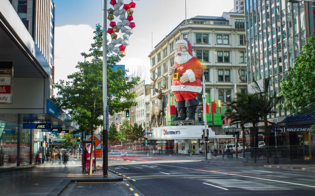 A giant Santa on Queen Street overlooks shoppers crossing the road in the Auckland Central City.