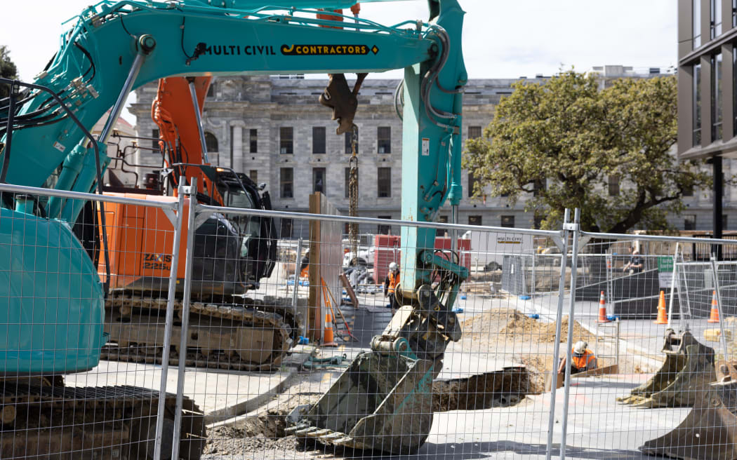 Groundworks underway for a new building at New Zealand's Parliament, with a heritage protected oak tree in the background, after it was moved from its original location closer to the original Parliament Building.