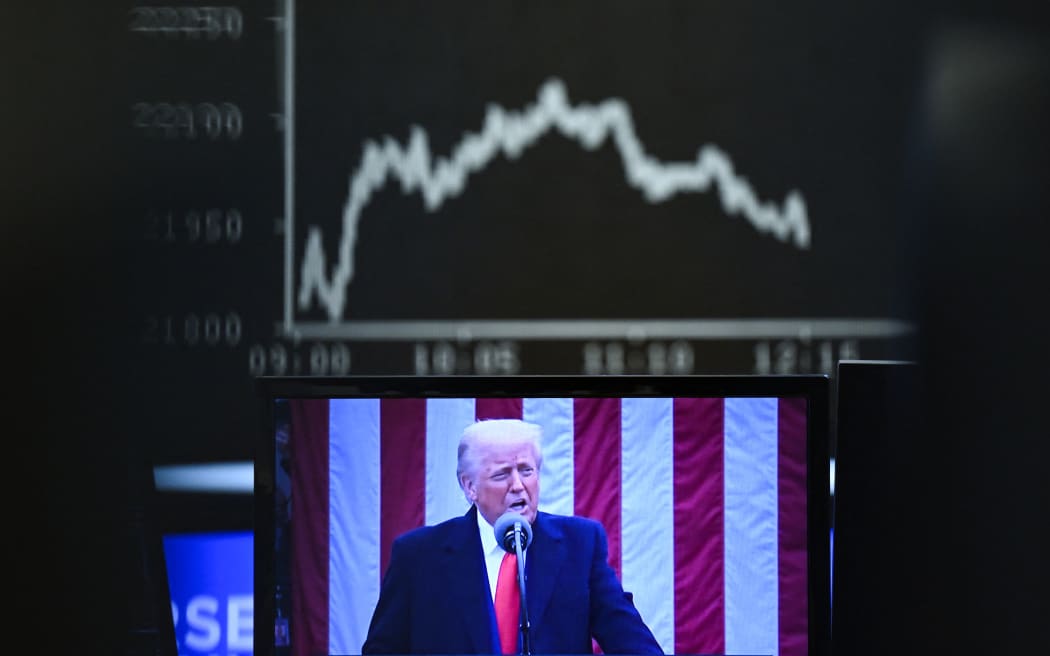 dpatop - 03 April 2025, Hesse, Frankfurt/Main: Behind a television monitor showing US President Donald Trump, the display board with the Dax curve shows falling share prices. The tariff package announced by US President Trump has pushed share prices sharply into negative territory. Photo: Arne Dedert/dpa (Photo by ARNE DEDERT / DPA / dpa Picture-Alliance via AFP)