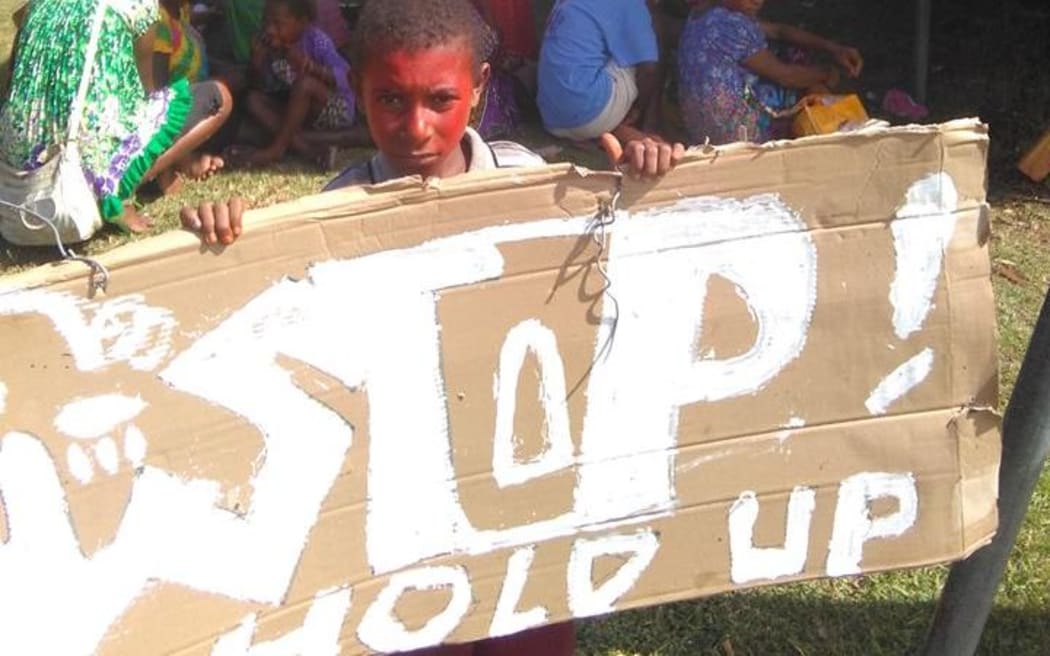 A child holds a sign at a protest in the PNG city of Madang demanding better law and order.