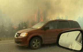 This screengrab from a video provided by Jordan Straker shows vehicles driving on the freeway as people evacuate from Yellowkife, Northwest Territories, Canada, on August 16, 2023. Thousands ordered to flee wildfires advancing on one of the largest cities in Canada's far north crammed into a local airport on August 17, 2023, to board emergency evacuation flights, as convoys snaked south to safety on the only open highway.