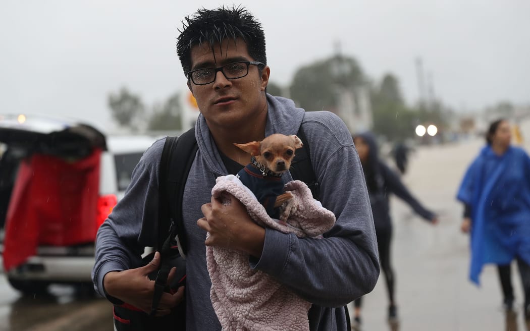 Evacuees - and their dogs - make their way to dry land after leaving their flooded homes.