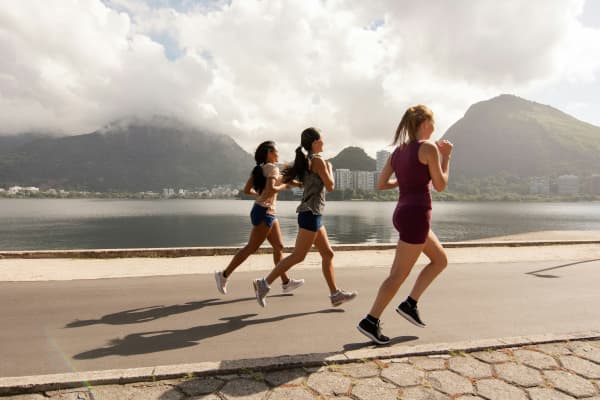 Group running outdoors with mountain and water in the background scenery.