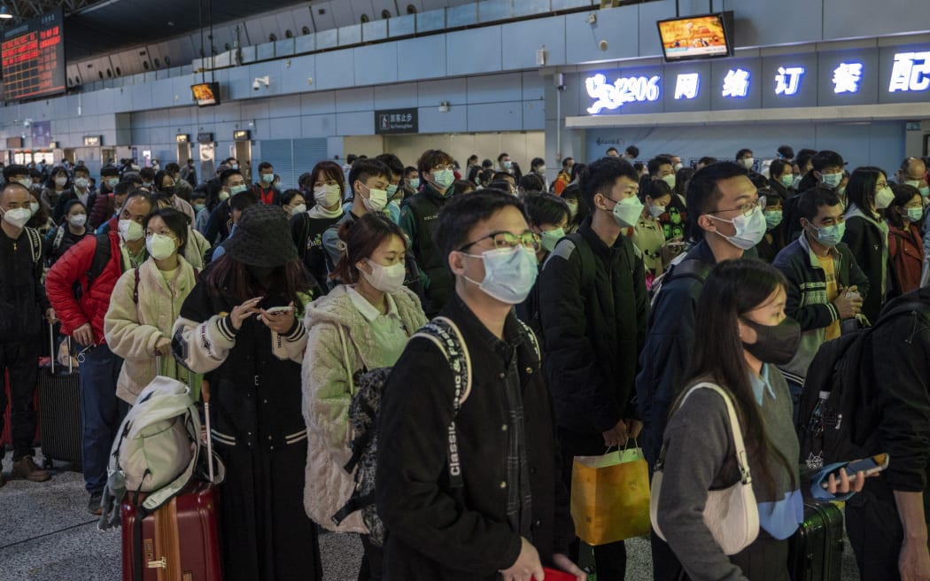 Passengers wearing face masks waiting at a ticket gates to board a high speed railway train in Guangzhou South railway station on January 15, 2023 in Guangzhou, China. China is currently experiencing Spring Festival travel season where millions of Chinese travel around the country before the celebration of the Chinese or Lunar New Year. (Photo by Vernon Yuen/NurPhoto) (Photo by Vernon Yuen / NurPhoto / NurPhoto via AFP)