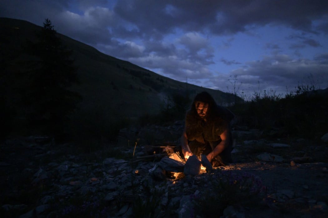 Guido Camia dressed as a Neanderthal Cave man lights a campfire in Chianale, in the Italian Alps, near the French border
