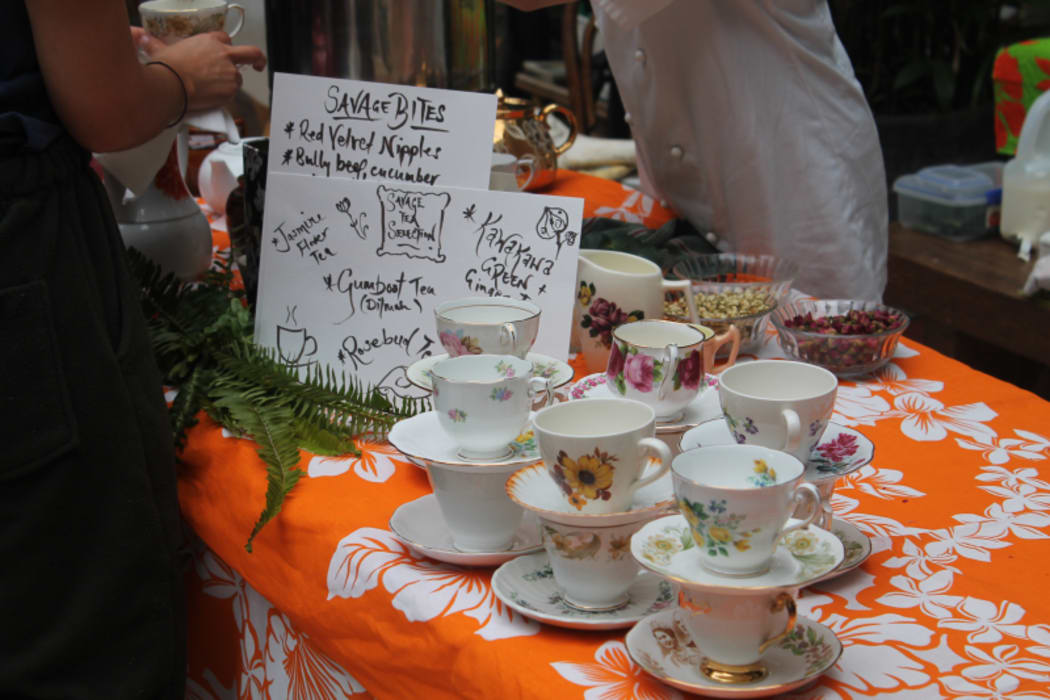 An image of china tea cups on a table and a sign displaying the range of teas available for purchase.