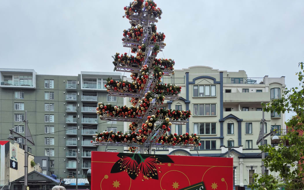 A Christmas tree made from light trusses with a lot of baubles, not a lot of plastic fir, placed outdoors in the streets of Wellington.
