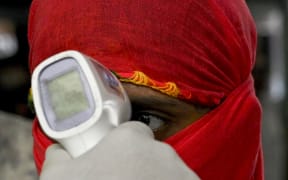 A health worker takes the body temperature of incoming passengers at a railway terminus following restrictions imposed by the state government amidst rising Covid-19 coronavirus cases Mumbai on April 7, 2021.