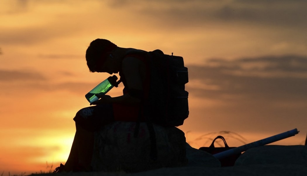 A child looks at his water bottle as the sun sets on June 15, 2021 in Los Angeles, California as temperatures soar in an early-season heatwave.